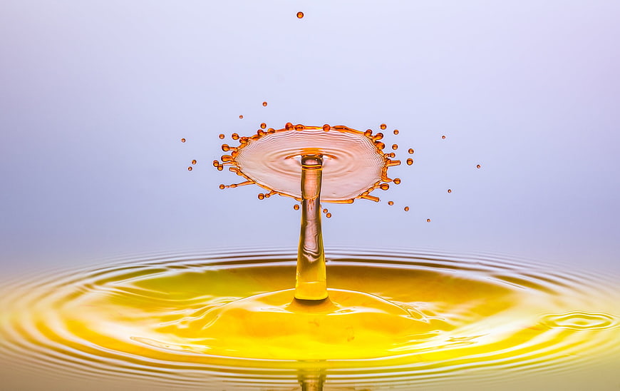 Golden liquid splash crown with droplets on clean background
