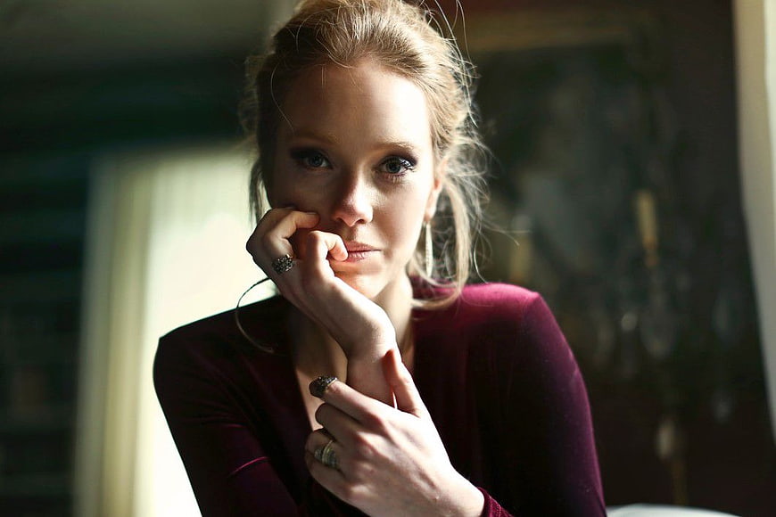 Pensive Woman in Burgundy Top with Rings