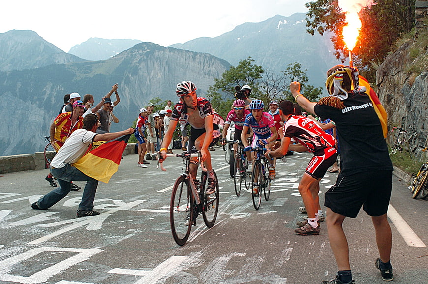 Cyclists racing on mountain road with Spanish fans and flares