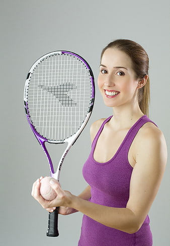 Smiling woman holding tennis racket and ball in purple outfit