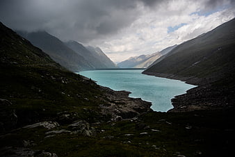 Dramatic turquoise alpine lake surrounded by dark mountains