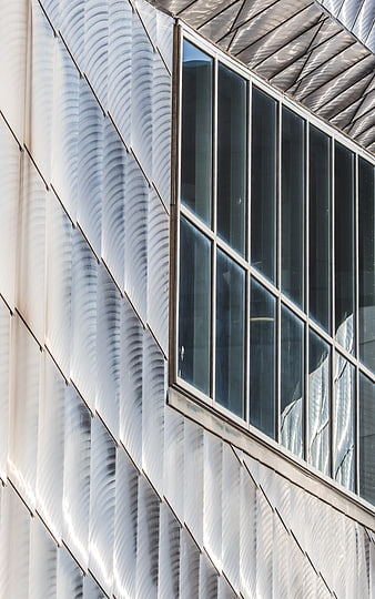 Modern building facade with textured white panels and glass windows
