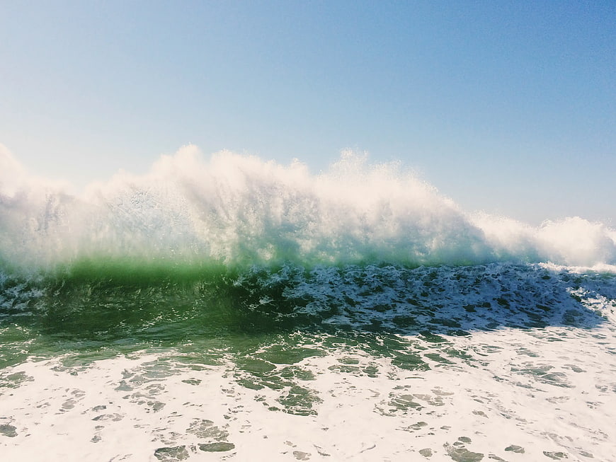 Powerful Green Ocean Wave Crashing Under Blue Sky