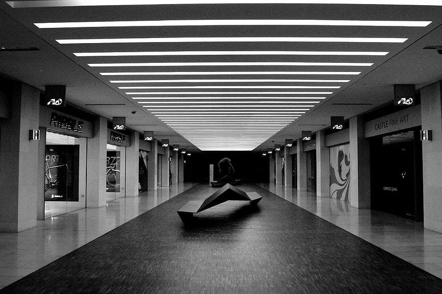 Black and white modern shopping mall corridor with geometric sculpture