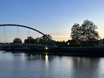 Modern Arch Bridge Over River at Dusk with Reflections