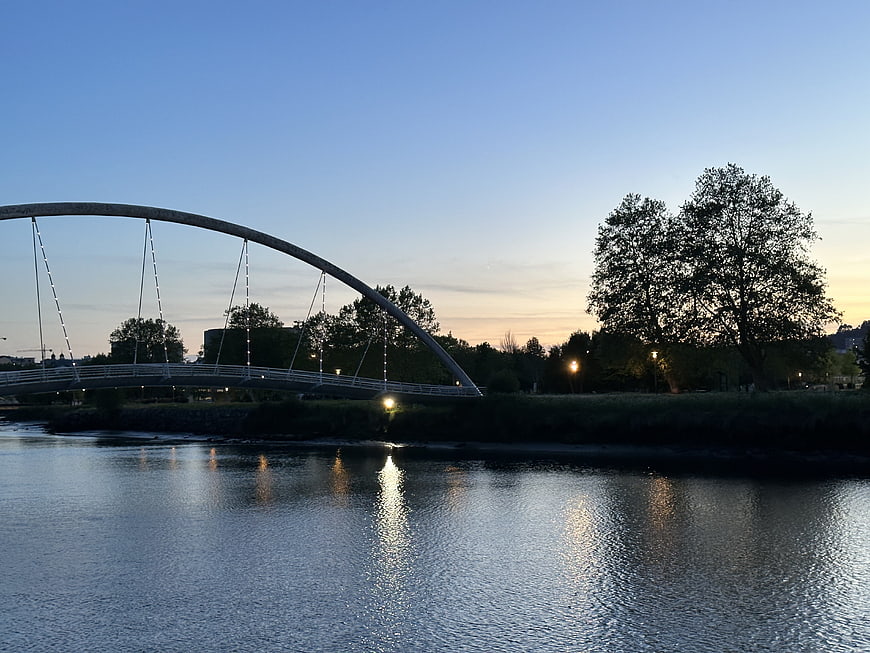 Modern Arch Bridge Over River at Dusk with Reflections