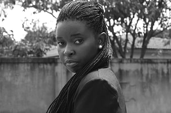 Black and white portrait of woman with braids looking back