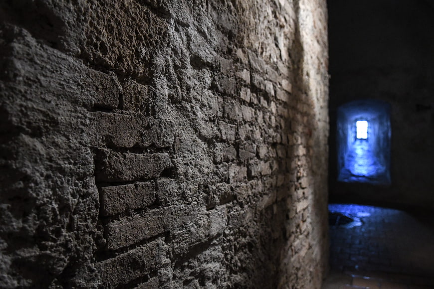 Dark medieval stone corridor with blue light from distant window