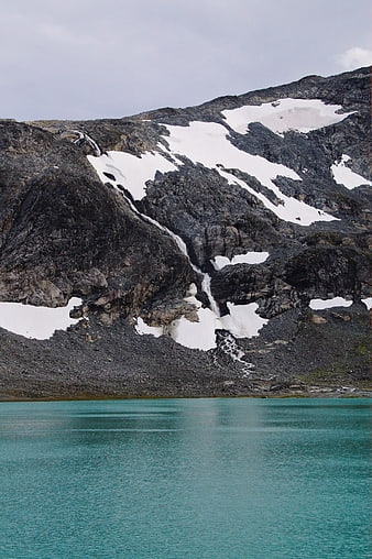 Turquoise alpine lake with snow-capped rocky mountain