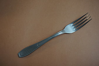 Black metal fork on brown background