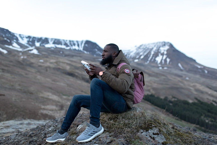 Man with headphones sitting on mountain ridge