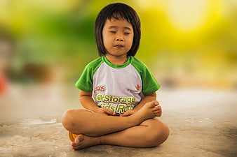 Cute little girl meditating in lotus position outdoors