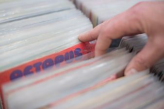 Hand selecting vinyl record from stack of music albums