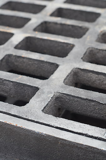 Close-up of black metal drainage grate texture