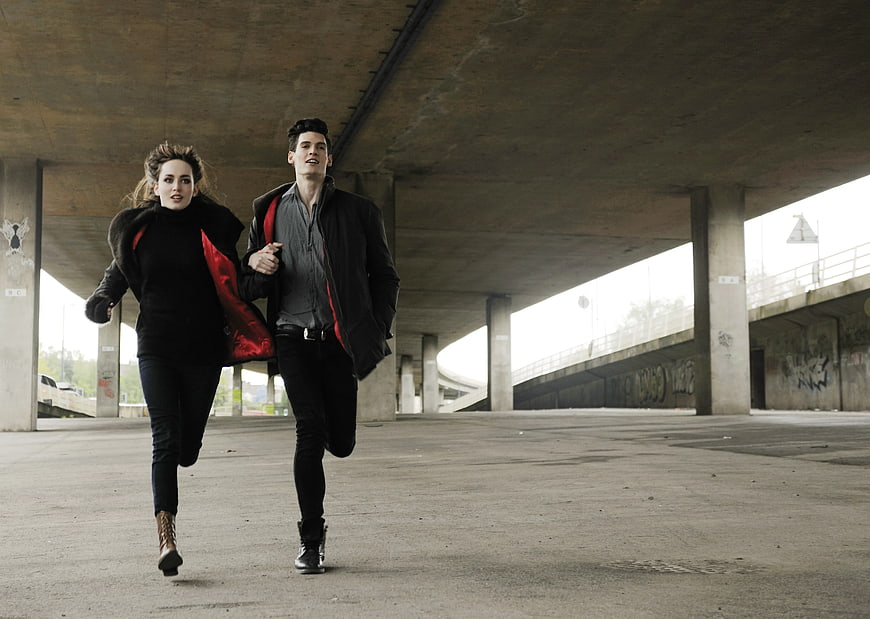 Young Couple Running Under Concrete Bridge