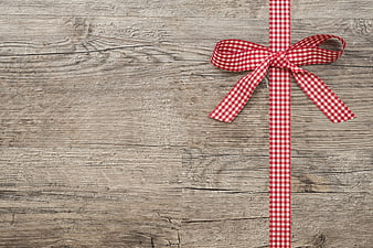 Red gingham ribbon bow on rustic wooden background