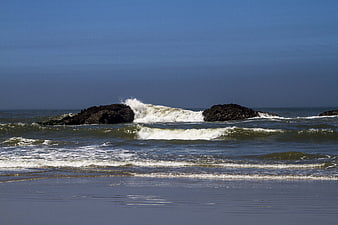 Ocean waves crashing on rocks at a sandy beach
