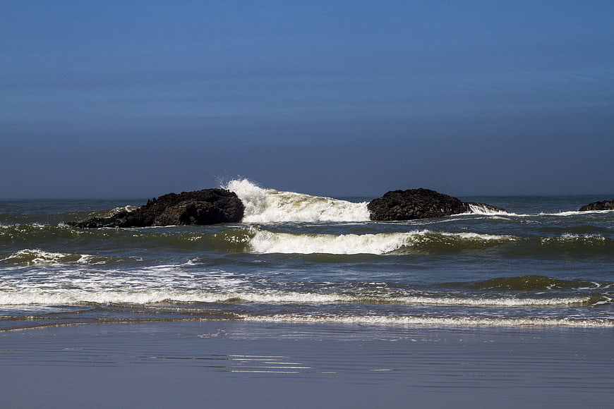Ocean waves crashing on rocks at a sandy beach