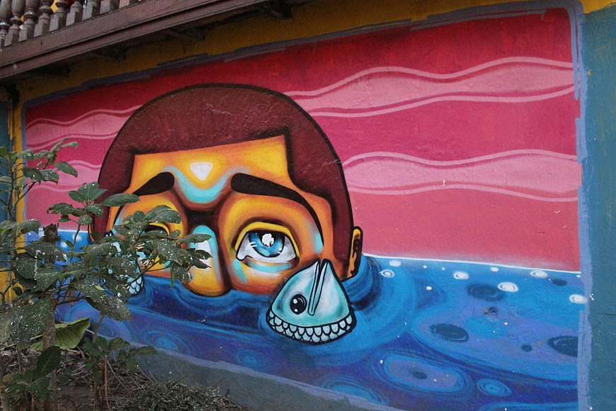 Colorful street art mural of man swimming with fish