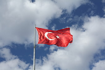 Turkish flag waving against blue sky with clouds