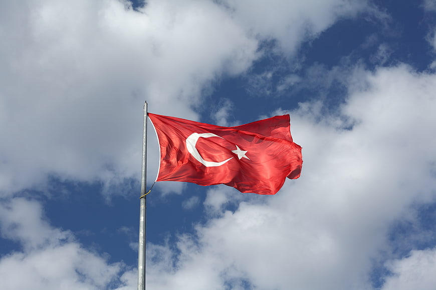 Turkish flag waving against blue sky with clouds