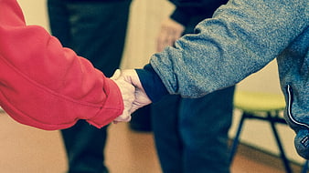 Close-up of two people holding hands in red and blue jackets