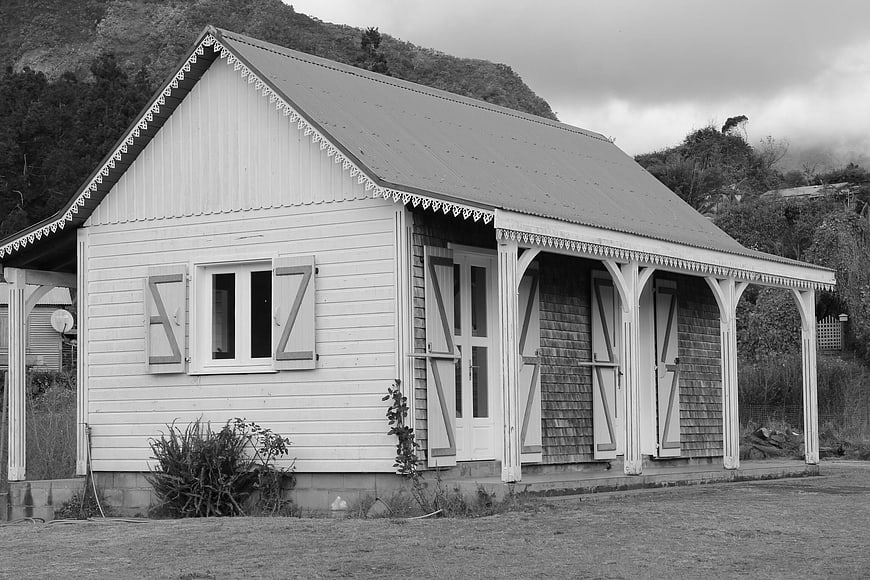 Black and white photo of a rustic wooden house with veranda