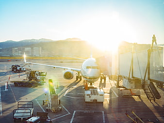 Commercial Airplane at Airport Gate with Jet Bridge and Ground Service Vehicles