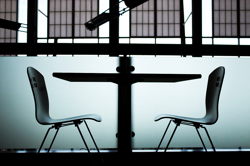 Silhouette of two chairs and table against frosted window