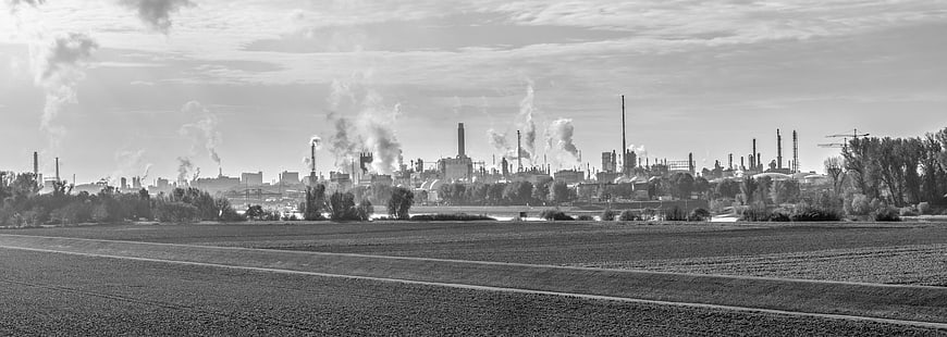 Black and white panoramic view of industrial chemical plant with smokestacks
