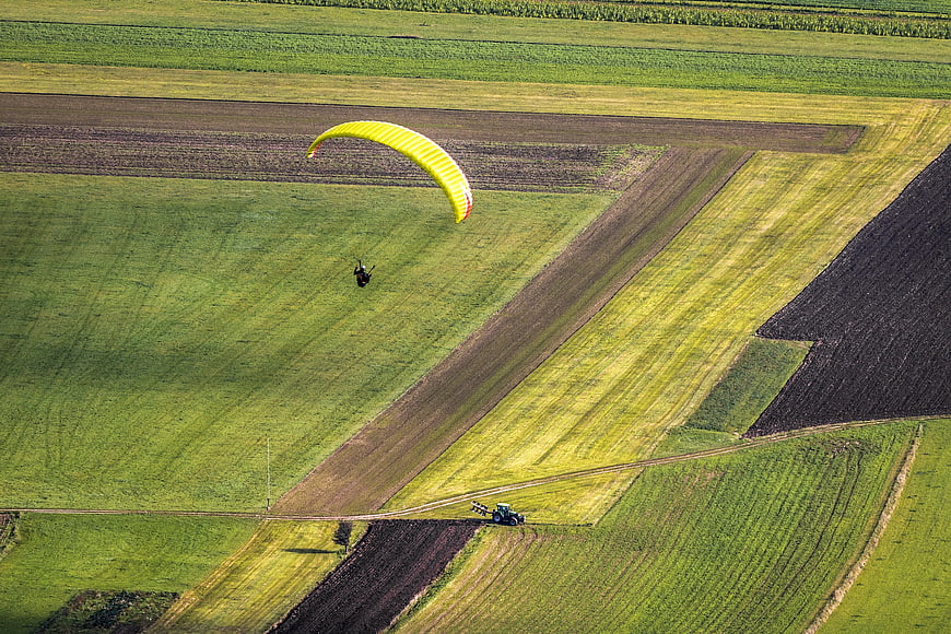 Aerial View of Paraglider Over Green Agricultural Fields