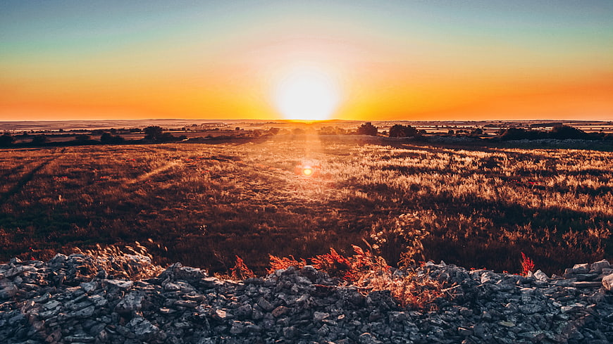 Golden Sunset Over Rolling Hills and Stone Wall