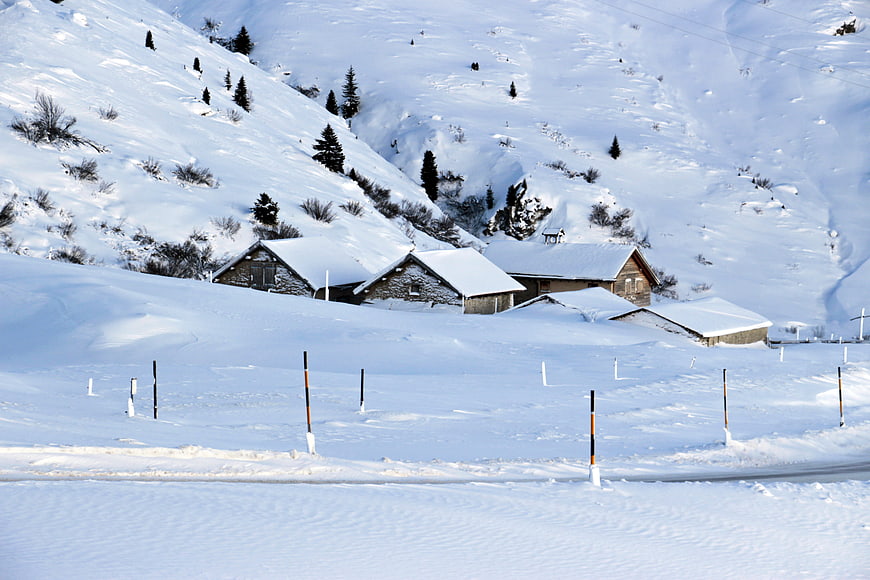 Snow-covered alpine village houses in winter mountain landscape