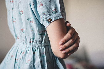Close-up of woman's hand holding arm in floral dress
