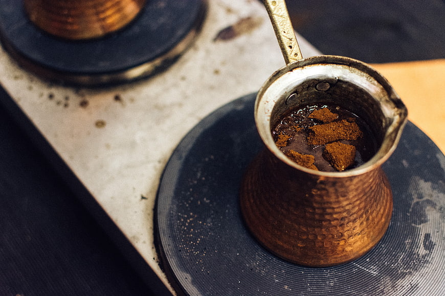 Copper coffee pot with grounds on gas stove burner