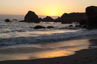 Golden Sunset Over Rocky Ocean Coastline with Gentle Waves
