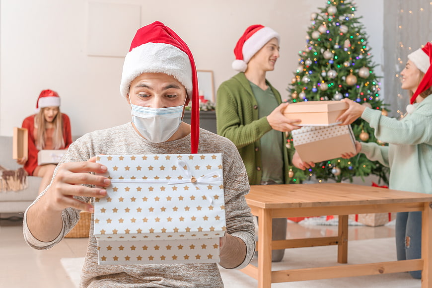 Man in Santa Hat and Face Mask Opening Christmas Gift