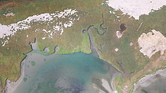 Aerial view of arctic coastline with snow patches and river delta