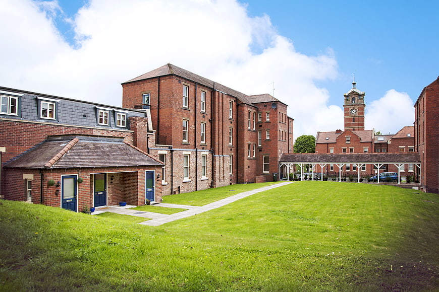 Historic Red Brick Buildings with Clock Tower and Green Lawn