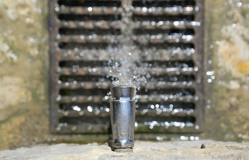 Close-up of water flowing from a metal tap into a drain