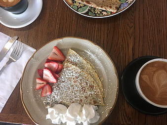Overhead view of sweet crepes with strawberries and coffee