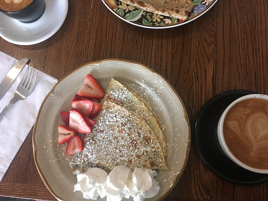 Overhead view of sweet crepes with strawberries and coffee