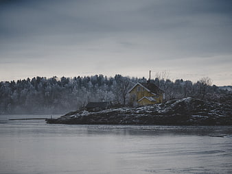 Yellow House on Rocky Shore in Winter Landscape