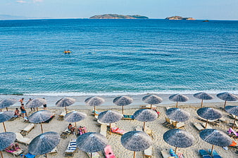 Aerial View of Beach with Straw Umbrellas and Blue Sea