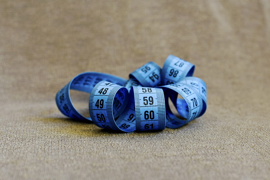 Blue measuring tape coiled on beige fabric background