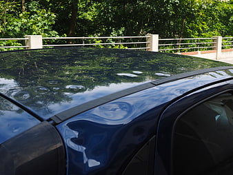 Close-up of hail damage on a dark blue car roof