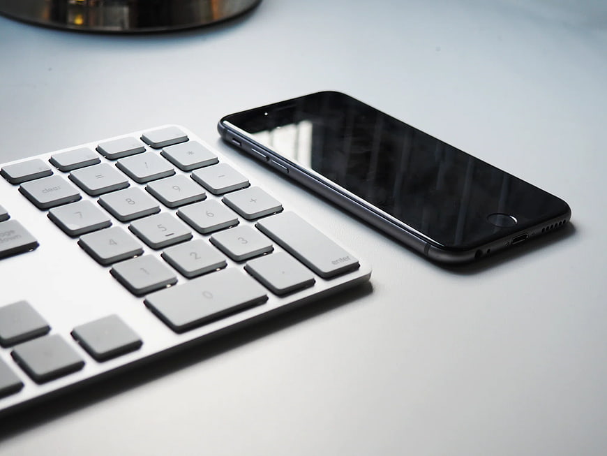 Modern Wireless Keyboard and Smartphone on White Desk