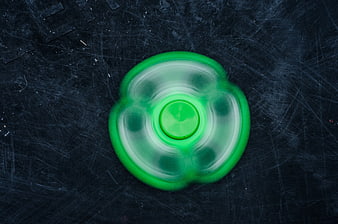 Spinning Green Fidget Spinner on Dark Textured Background
