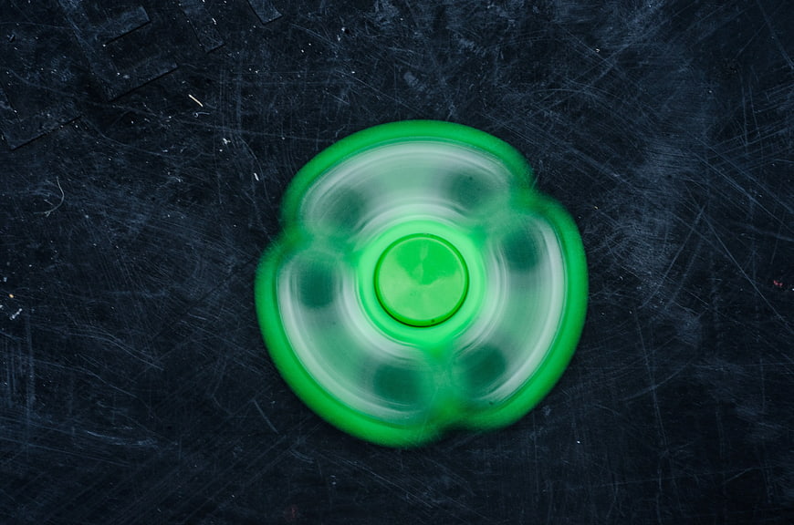 Spinning Green Fidget Spinner on Dark Textured Background
