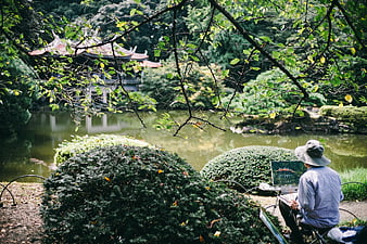 Artist painting traditional Asian pavilion in serene garden